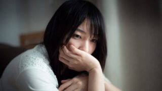 膝を抱えて口を押さえる女性