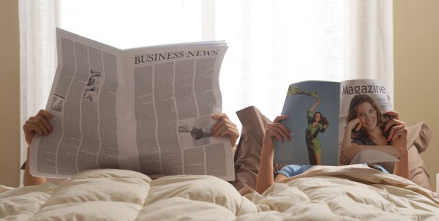 ベッドで新聞や雑誌を読む夫婦