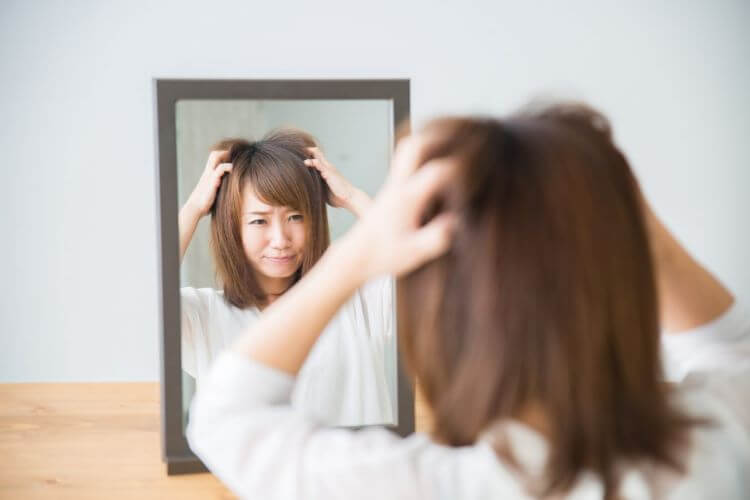 鏡の前で髪をくしゃくしゃする女性