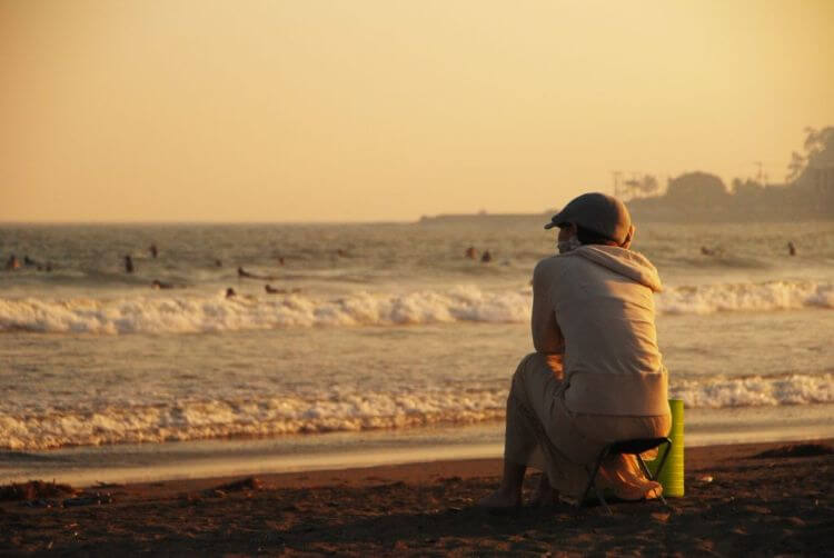 夕暮れの海辺に一人黄昏る人