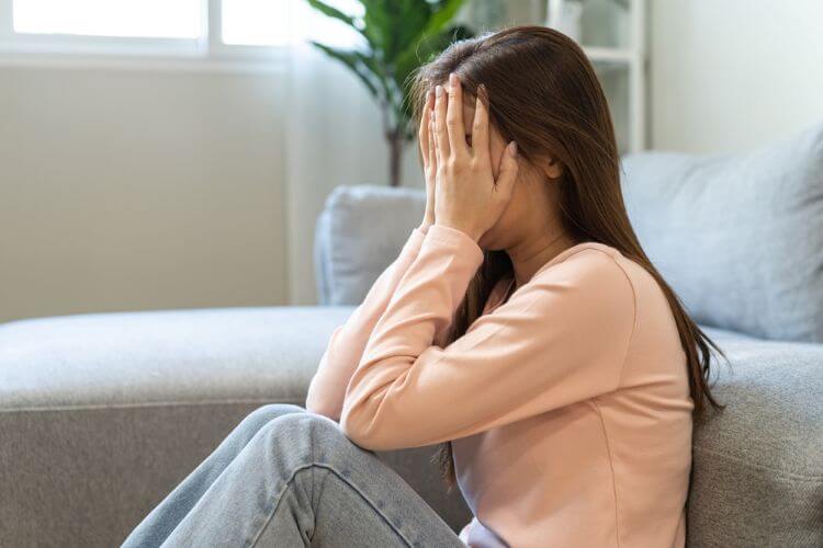 後悔で顔を覆って悩む女性