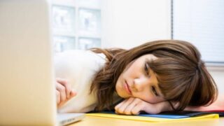 机にうなだれる女性