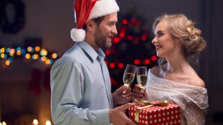 妻にプレゼントを渡すサンタ帽をかぶった夫
