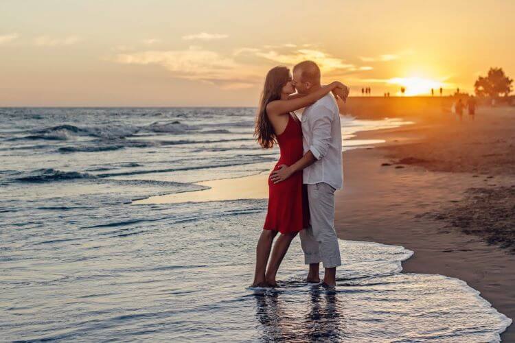 夕暮れの海辺でキスするカップル